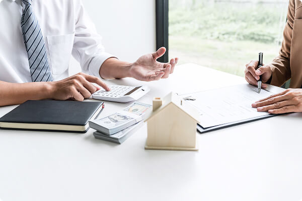 査定と打ち合わせを行う様子、机上に広がる資料と住宅模型